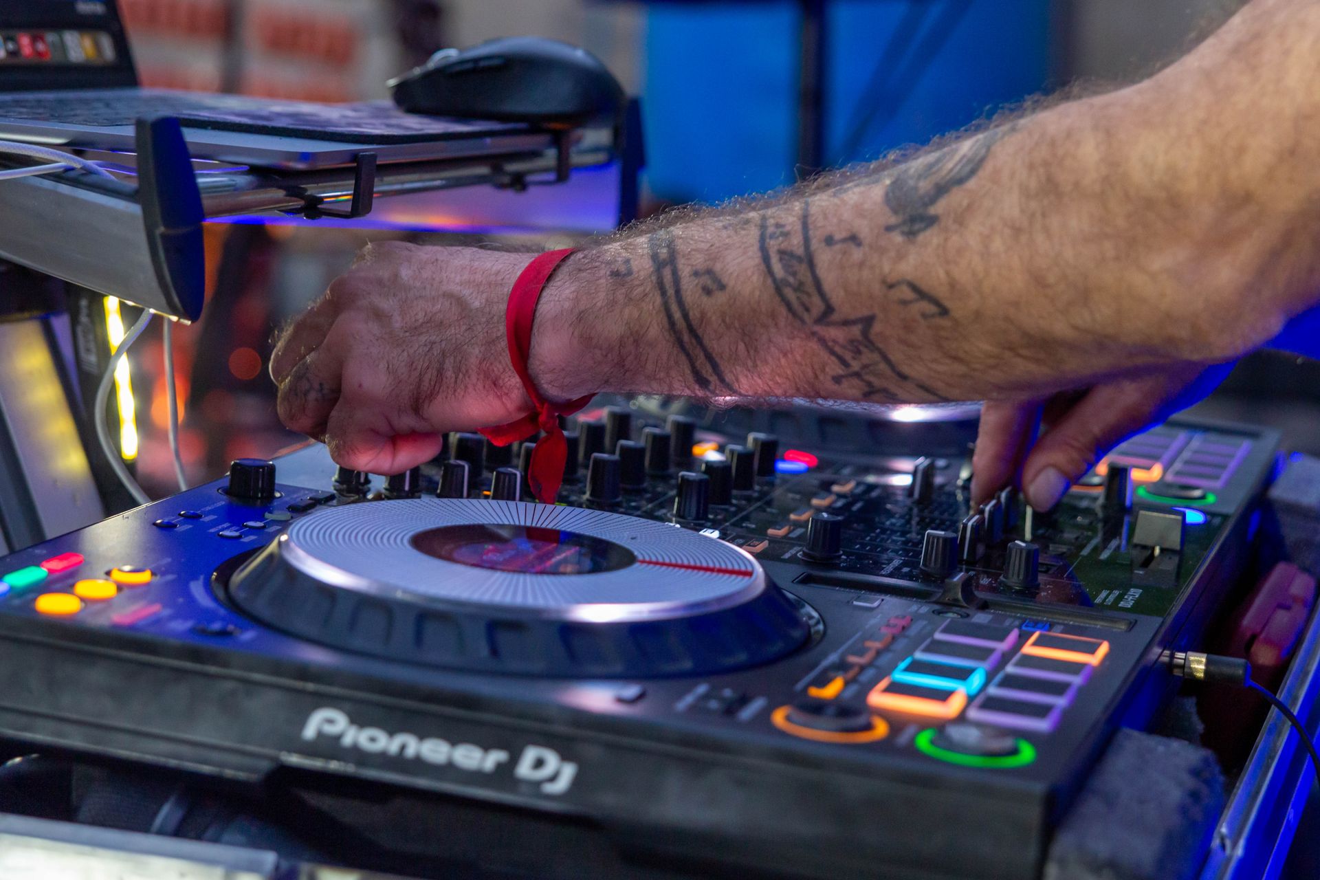 A DJ adjusting a mixing controller under blue event lighting.