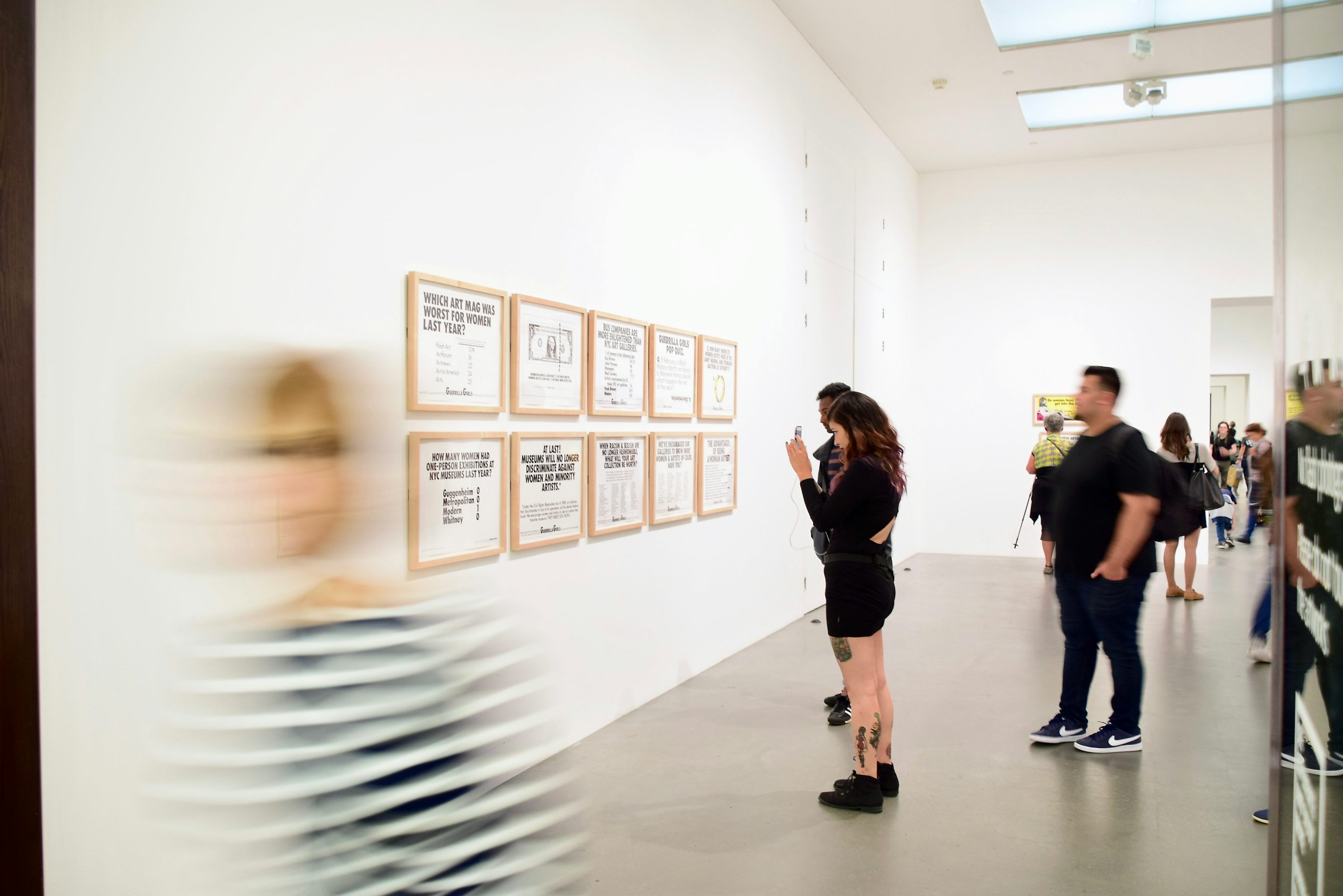 Visitors viewing framed works in a bright gallery at Tate Modern in London.