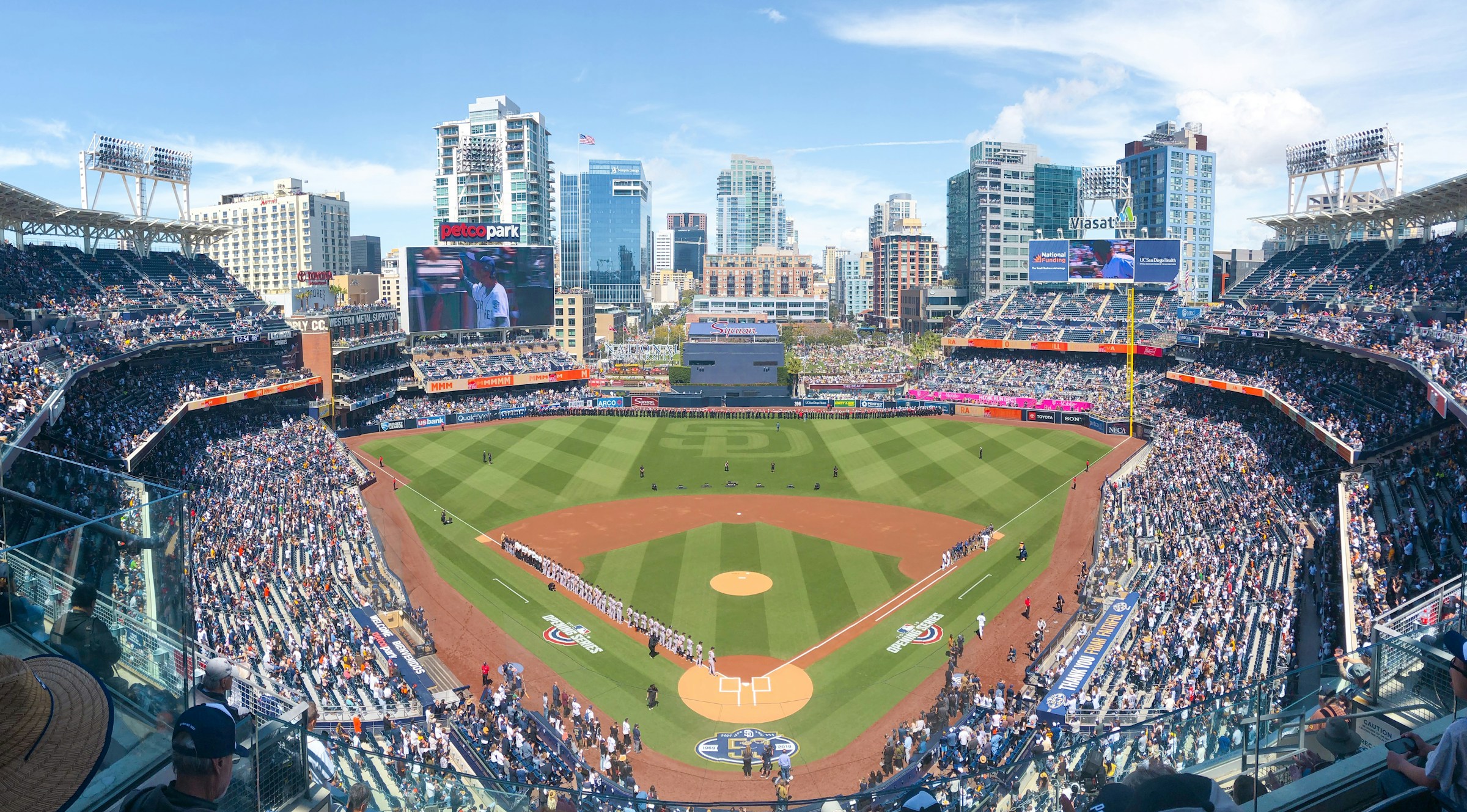 Spectators at Petco Park in San Diego, with baseball teams lined along the baselines.